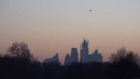 Ein-Hubschrauber-Fliegt-Bei-Sonnenuntergang-über-Dem-Gherkin-Wolkenkratzer-Und-Der-Skyline-Der-City-Of-London