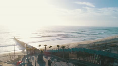 Aerial-shot-of-the-wall-at-the-Tijuana---San-Diego-border-in-the-beach-at-sunset