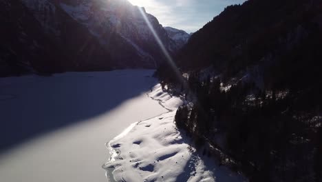 Luftaufnahme-über-Einem-Zugefrorenen-See-In-Einem-Wunderschönen-Tal,-Umgeben-Von-Riesigen-Schneebedeckten-Bergen-Im-Klöntal,-Schweiz
