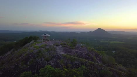 Fast-aerial-shot-of-Australia's-landscape,-mount-Tinbeerwah-lookout-at-sunset-with-people-and-amazing-view