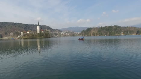 Flying-over-Bled-lake-and-view-the-island-with-small-church-located-in-the-middle-of-the-Lake-Bled,-Slovenia