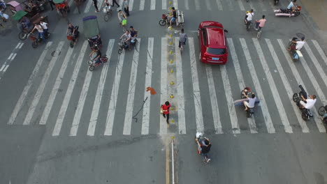 Crosswalk-in-a-textile-market-street-with-driving-motorbikes-and-rickshaws-loaded-with-textile-rolls-in-Guangzhou,-China,-Asia