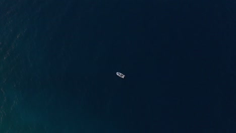 Kleines-Weißes-Fischerboot,-Das-Abends-Auf-Dem-Tiefblauen-Meer-Schwimmt