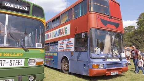 An-old-fashioned-single-deck-bus-next-to-a-double-decker-bus-that-has-been-converted-into-a-kids-play-area-bus