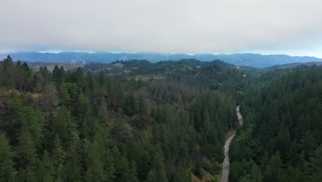 Aerial-drone-flyover-of-the-redwood-forests,-mountains-and-think-clouds-and-fog-in-the-horizon-of-Northern-California