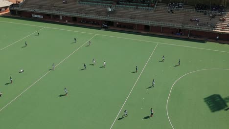 Eine-Diagonal-Nach-Rechts-Schwenkende-Drohnenaufnahme-Eines-Feldhockeyspiels-Unter-Sonnigen-Bedingungen