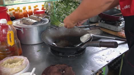 Toma-En-Cámara-Lenta-Del-Vendedor-De-Comida-Callejera-Rompiendo-Un-Huevo-En-Un-Wok-Caliente