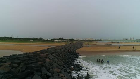 Group-of-Patriotic-youthful-men-hold-Indian-national-flag-standing-on-a-rocky-beach-front-with-waves-crashing