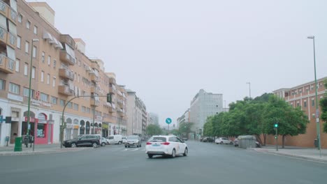 Cars-drive-through-intersection-in-Seville,-Spain,-on-foggy-morning,-Slow-Motion