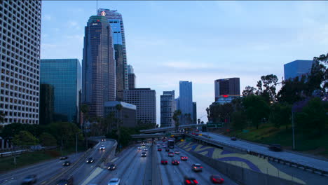 Zeitraffer-Des-Autobahnverkehrs-Und-Der-Innenstadt-Von-Los-Angeles-In-Der-Abenddämmerung-Mit-Lichtspuren
