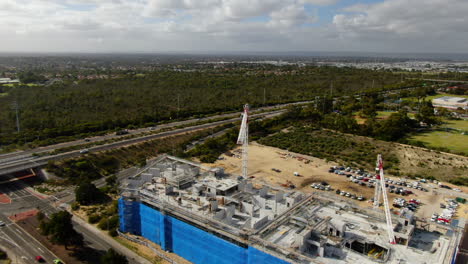 Drone-shot-orbiting-two-cranes-working-on-construction-site-opposite-reid-highway-and-Balcatta-Rd,-Perth-Western-Australia