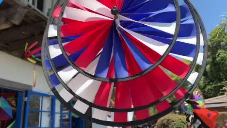 Colorful-and-bright-pinwheels-spinning-in-front-of-a-local-retail-store-that-specializes-in-kites,-wind-chimes,-windsocks,-and-other-lawn-accessories