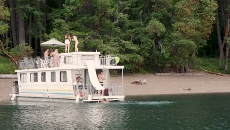 Young-people-parting-on-a-houseboat-on-lake-Cowichan-with-man-jumping-into-water
