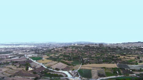 Aerial-drone-footage-flying-towards-the-Verdala-Palace-with-patchwork-countryside-below-of-fields-for-local-farming-and-agriculture