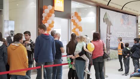 Crowd-of-people-waiting-for-Xiaomi-store-opening,-panning-right-slowmo-shot