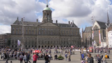 Establishing-shot-of-the-Royal-Palace-at-the-crowded-Dam-Square-with-a-tram-passing-by