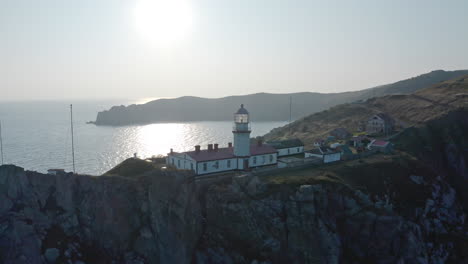Slow-aerial-pivot-shot-around-Gamov-lighthouse-standing-on-a-rocky-steep-cliff,-on-the-sunset