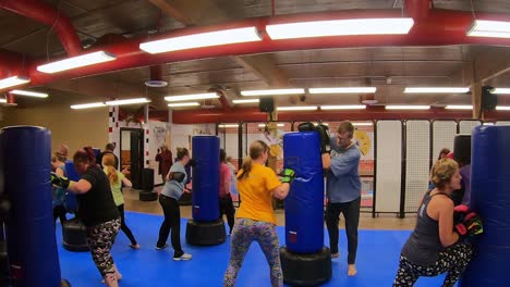 Adult-students-practicing-kicks-and-strikes-while-participating-in-a-self-defense-class-at-martial-arts-school