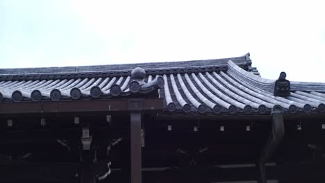 Walking-by-a-rooftop-made-by-Japanese-traditional-rooftop-panels-in-Kyoto,-Japan-with-soft-lighting