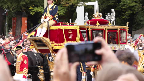 Queen-Maxima-and-King-Willem-Alexander-of-the-Dutch-royal-family-passing-by-in-horse-and-carriage-waving-at-the-crowds-along-the-pathway-from-the-House-of-Representatives-to-the-Noordeinde-Palace