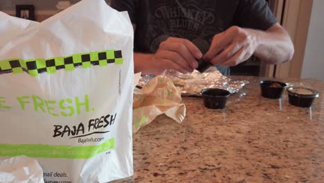 Smooth-reveal-shot-of-a-man-dipping-chips-into-salsa,-from-Baja-Fresh,-fast-food