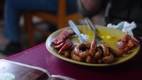 Salchicha-De-Cerdo-Y-Plato-De-Carne-Se-Ha-Servido-En-Un-Restaurante-En-Un-Plato-Amarillo-Con-Cuchillo-Y-Tenedor