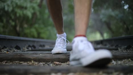 Toma-En-Cámara-Lenta-De-Alguien-Caminando-Sobre-Vías-De-Tren-Abandonadas-Hacia-La-Cámara