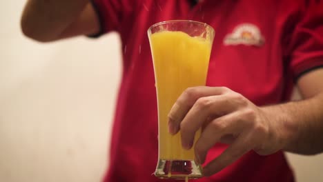 Slow-Motion-Of-Man-Dropping-Ice-Into-A-Glass-Of-Orange-Juice