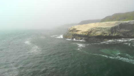 Static-Aerial-of-Cliffside-as-Pelicans-Disappear-into-Fog