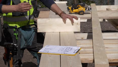 Carpenters-at-construction-site,-detail-shot-of-discussion-around-blueprint