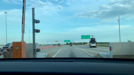 Cars-drive-through-crossing-barriers-at-the-entrance-of-the-Ohio-Turnpike-interstate-highway-in-Ohio-while-driving
