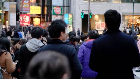 Crowds-of-people-crossing-the-street-in-downtown-Tokyo,-Japan,-in-the-evening