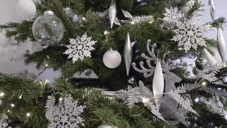 Low-Angle-View-Of-Christmas-Tree-Adorned-With-Silver-Glitter-Snowflakes-And-Decorations