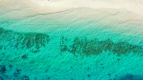 Lebendige-Farben-Des-Türkisfarbenen-Meerwassers-über-Wunderschönen-Mustern-Von-Korallenriffen-Und-Felsen,-In-Der-Nähe-Des-Weißen-Sandes-Eines-Exotischen-Strandes-In-Der-Karibik