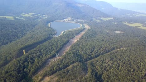 Water-reservoir-near-the-Warragamba-bushfire-zone-in-Australia-with-smoke-in-the-distance,-Aerial-drone-hover-shot