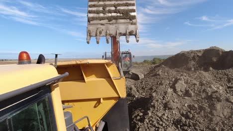 Vista-De-Cámara-De-Acción-De-Un-Camión-Volquete-Cargado-Con-Tierra-En-Un-Gran-Sitio-De-Construcción