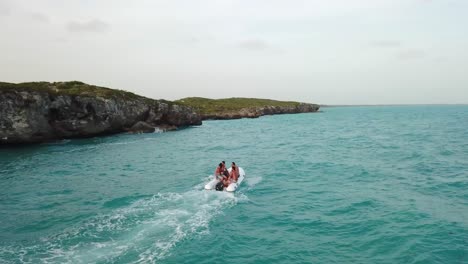 Group-of-young-males-in-a-small-boat-driving-along-the-cliffs-in-Providenciales-in-the-Turks-and-Caicos-archipelago
