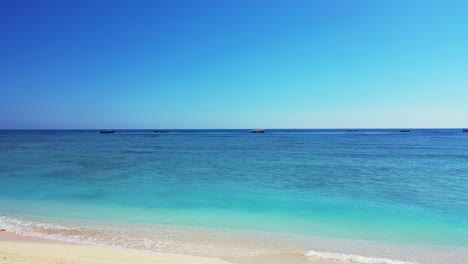 Quiet-exotic-beach-with-white-sand-washed-by-calm-clear-water-of-turquoise-lagoon-and-blue-sea-horizon-under-bright-sky-in-Thailand