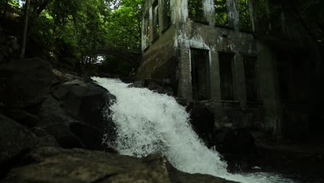 Waterfall-pouring-down-the-side-of-an-abandoned-mill-in-Gatineau-Park,-Quebec