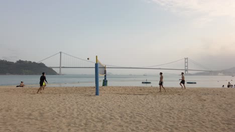 Young-Men-playing-beach-Volleyball-in-Hong-Kong,-Lido-beach