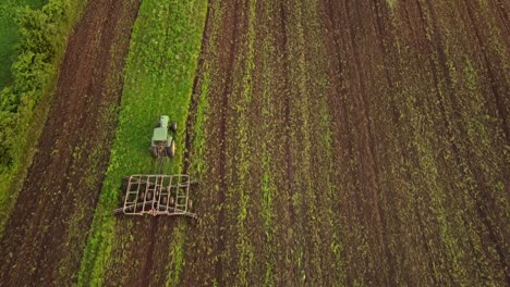 High-Angle-View-Of-An-Agricultural-Tractor-Cultivating-The-Soil-On-The-Farmland-In-Monroe-County,-Michigan---top-down-shot