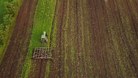 Vista-De-ángulo-Alto-De-Un-Tractor-Agrícola-Cultivando-El-Suelo-En-Las-Tierras-De-Cultivo-En-El-Condado-De-Monroe,-Michigan---Toma-De-Arriba-Hacia-Abajo