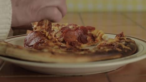 Hand-grabbing-slice-of-pepperoni-pizza-close-up-shot