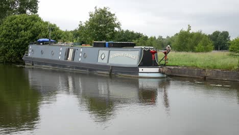 British-long-canal-narrow-boat-moored-along-scenic-English-marine-countryside-waterway