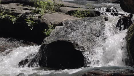 Nahaufnahme-Von-Wasser,-Das-Felsen-Und-Wasserfall-Hinunterfließt