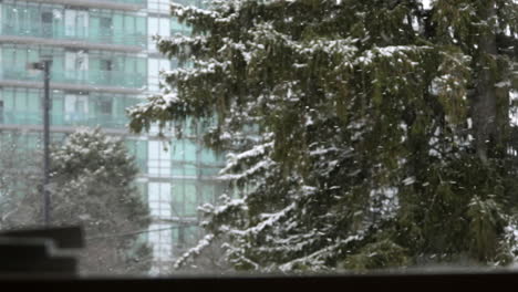 Blick-Durch-Ein-Fenster,-Wo-In-Der-Stadt-Schnee-Fällt