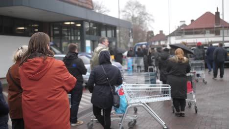 People-are-queueing-outside-of-the-supermarket-chain-Aldi-before-it-is-open-in-the-morning-to-shop-and-stock-up-on-food-during-the-Corona-virus-crisis-and-in-preparation-for-quarantine-in-the-UK