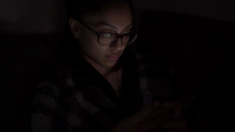 Mujer-Asiática-étnica-Con-Gafas-Viendo-Videos-En-El-Móvil-Por-La-Noche