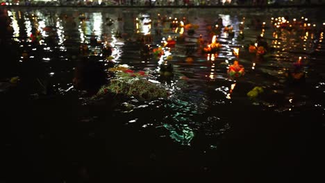 Una-Pequeña-Niña-Tailandesa-Nada-Entre-Decenas-De-Loy-Krathongs-En-Los-Canales-De-La-Ciudad-Mientras-Otras-Personas-Hacen-Flotar-Krathongs-Y-Rezan-Por-La-Noche-Durante-El-Festival-Loi-Krathong-En-Korat,-Tailandia