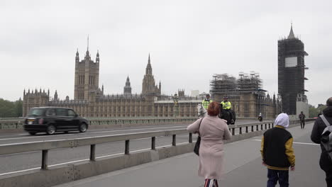 Zwei-Polizisten-Auf-Pferden-Laufen-Während-Des-Coronavirus-Ausbruchs-über-Eine-Fast-Menschenleere-Westminster-Brücke-Und-An-Den-Parlamentsgebäuden-Vorbei